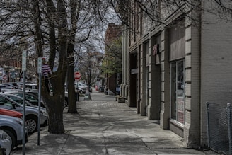 a city street lined with parked cars next to tall buildings