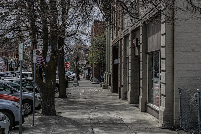 a city street lined with parked cars next to tall buildings