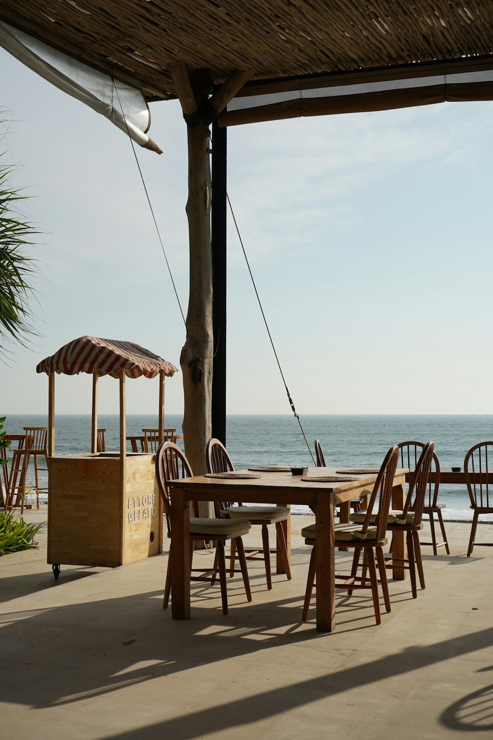 a wooden table and chairs on a patio near the ocean