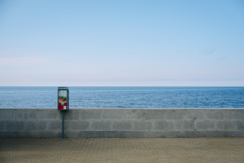 a parking meter sitting on the side of a road next to the ocean