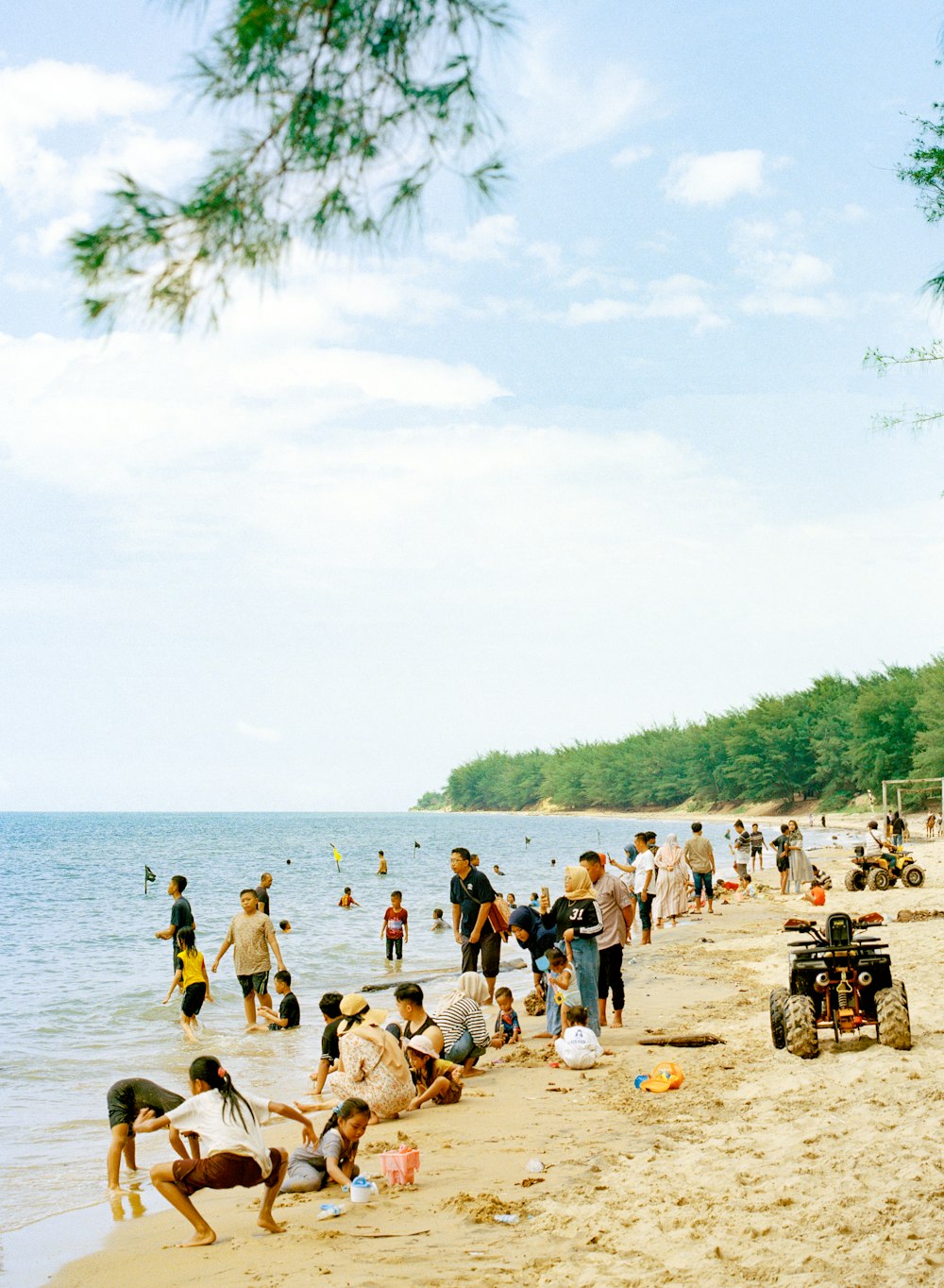 un groupe de personnes debout au sommet d’une plage de sable