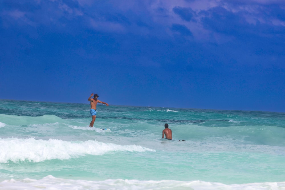 two people in the ocean playing with a kite