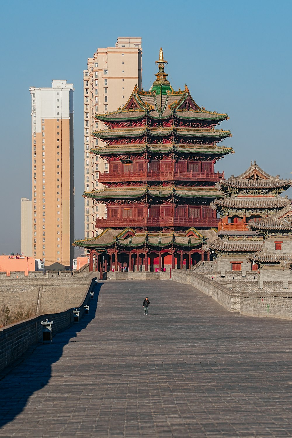 a person walking down a walkway in front of a tall building