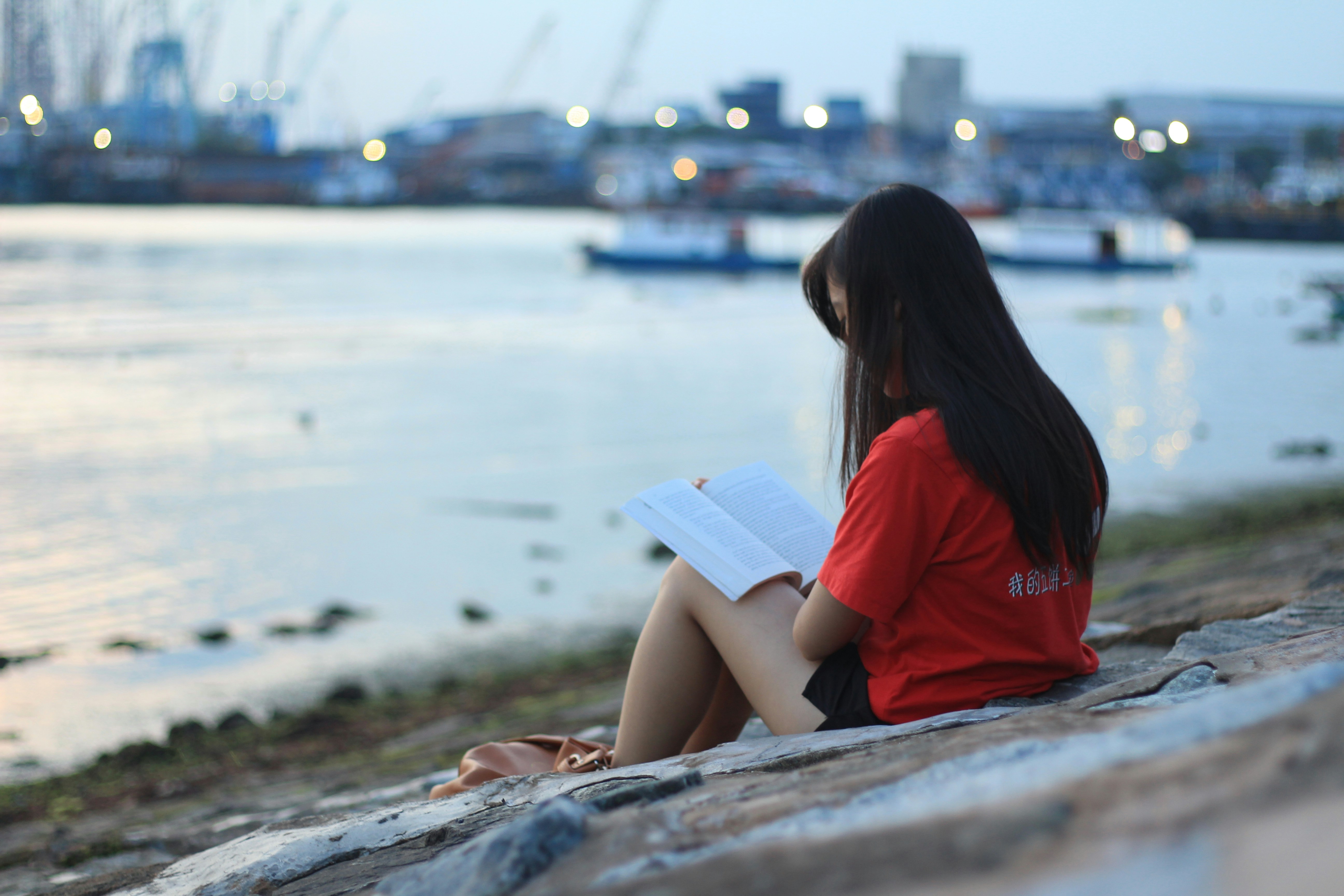a woman sitting on a rock reading a book