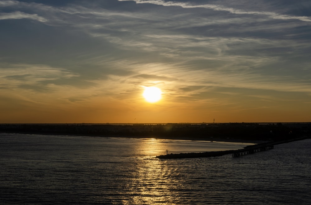 a large body of water with a sunset in the background