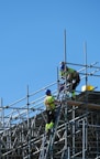 two construction workers working on scaffolding on a building