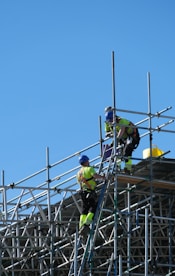 two construction workers working on scaffolding on a building