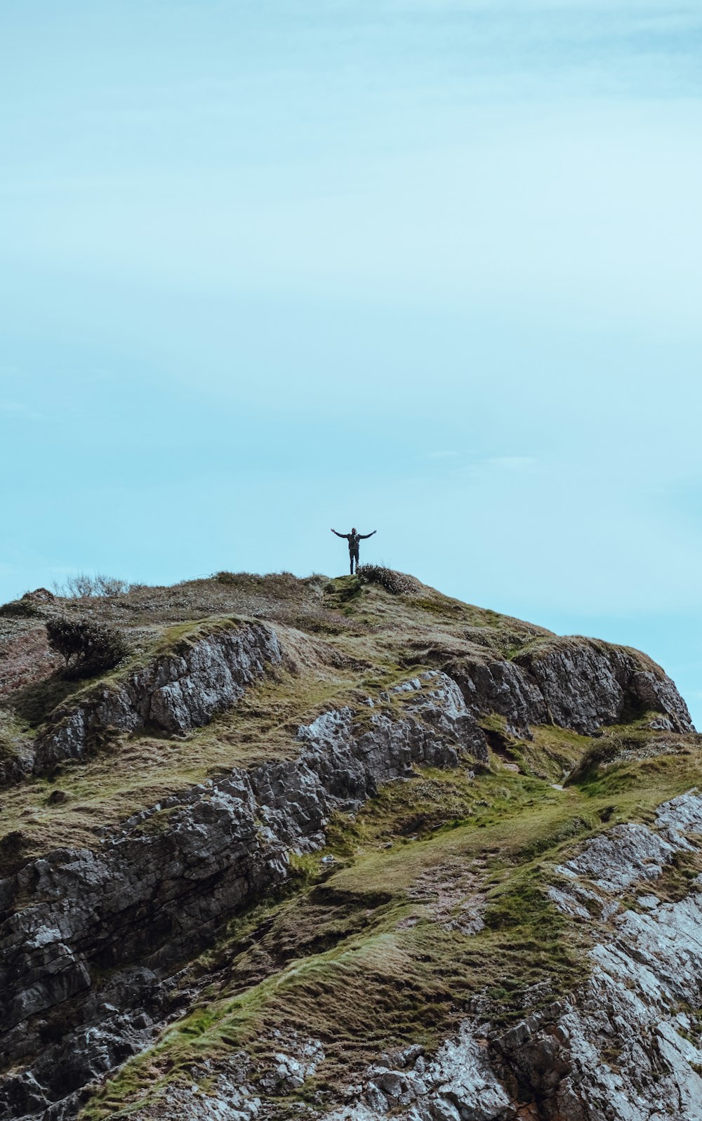 une personne debout au sommet d’une colline rocheuse