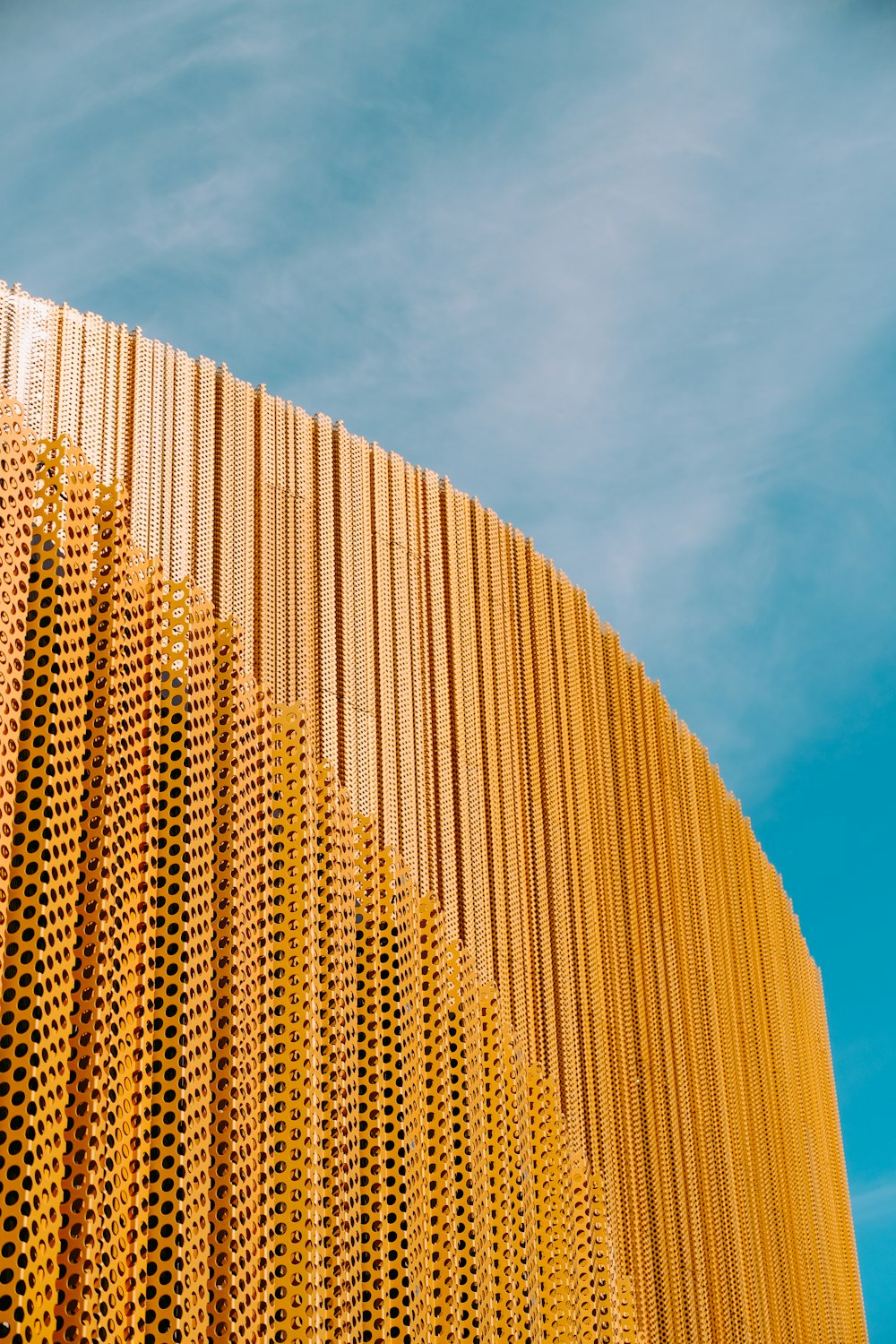 un grand bâtiment jaune aux murs perforés sur un ciel bleu