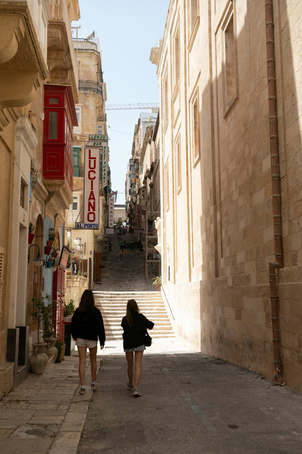 two women walking down a narrow street in a city