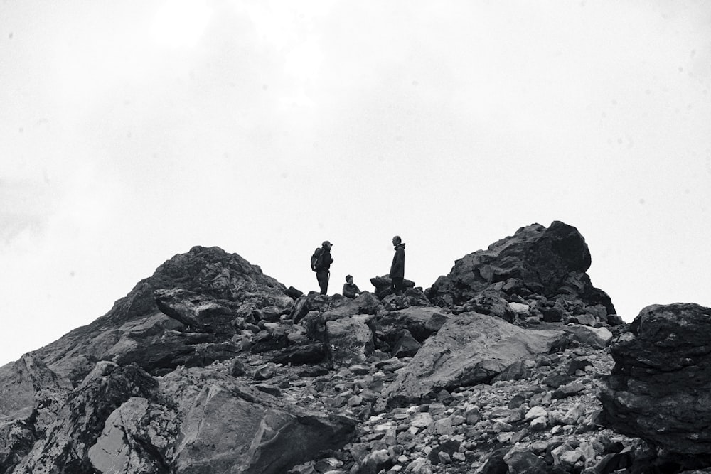 a couple of people standing on top of a rocky hill