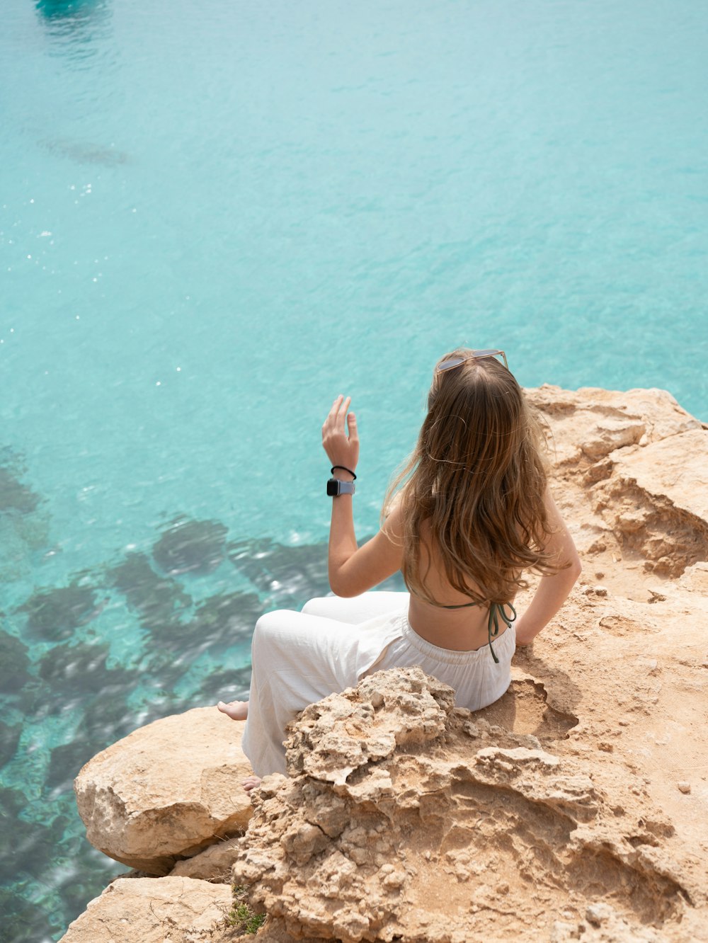 uma mulher sentada em uma rocha à beira da água