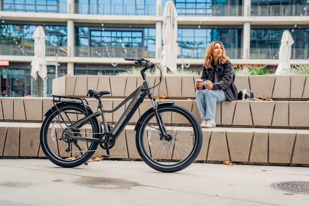 a woman sitting on a bench next to a bike