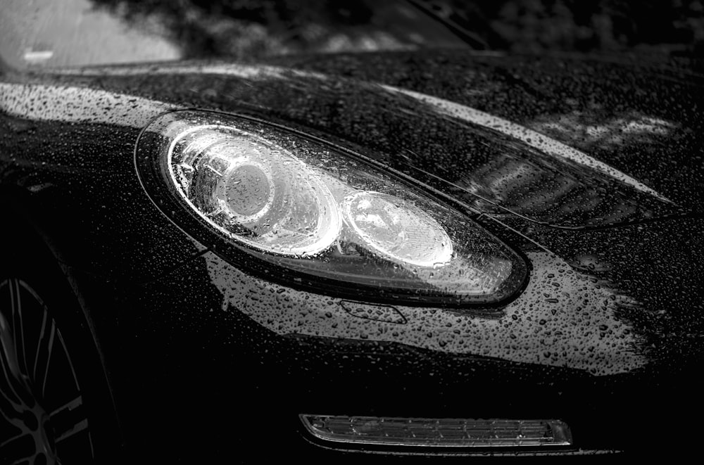 a close up of a car's headlight on a rainy day
