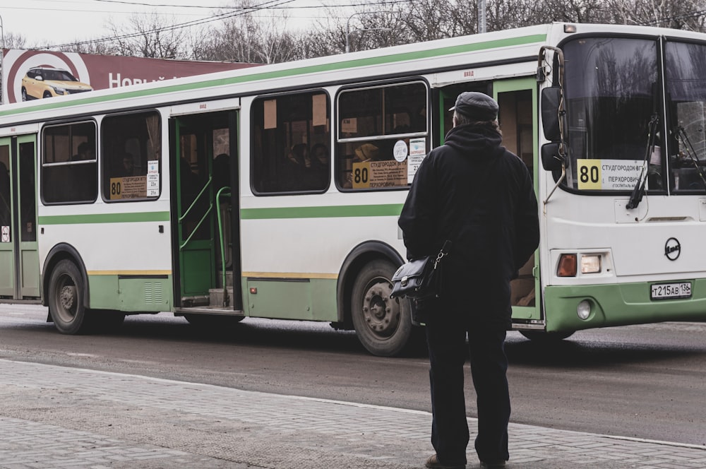 a man standing in front of a green and white bus