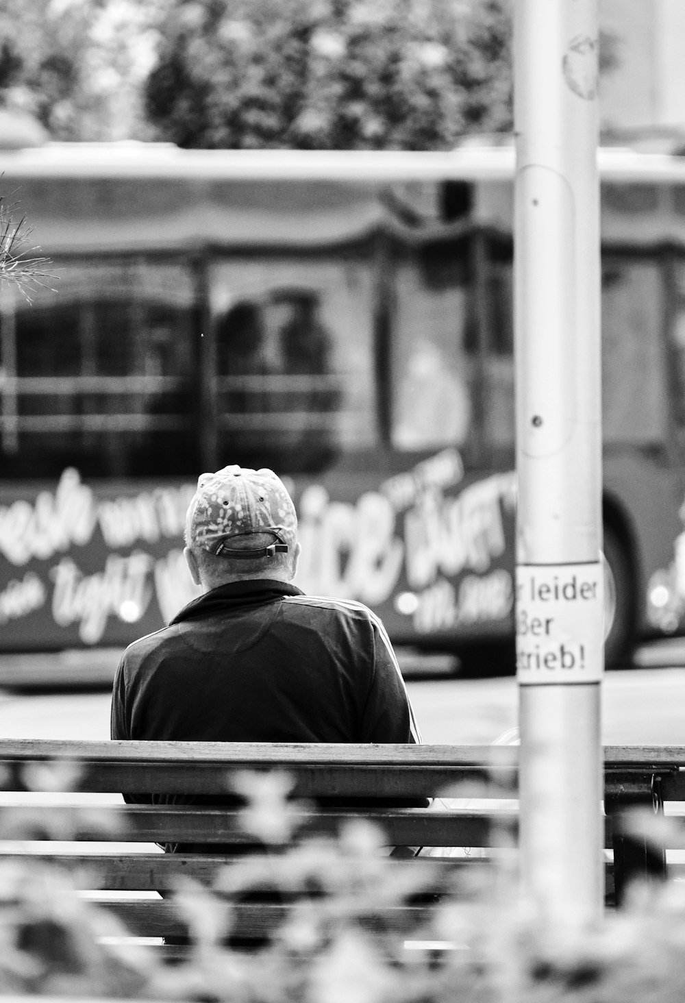 a man sitting on a bench in front of a bus