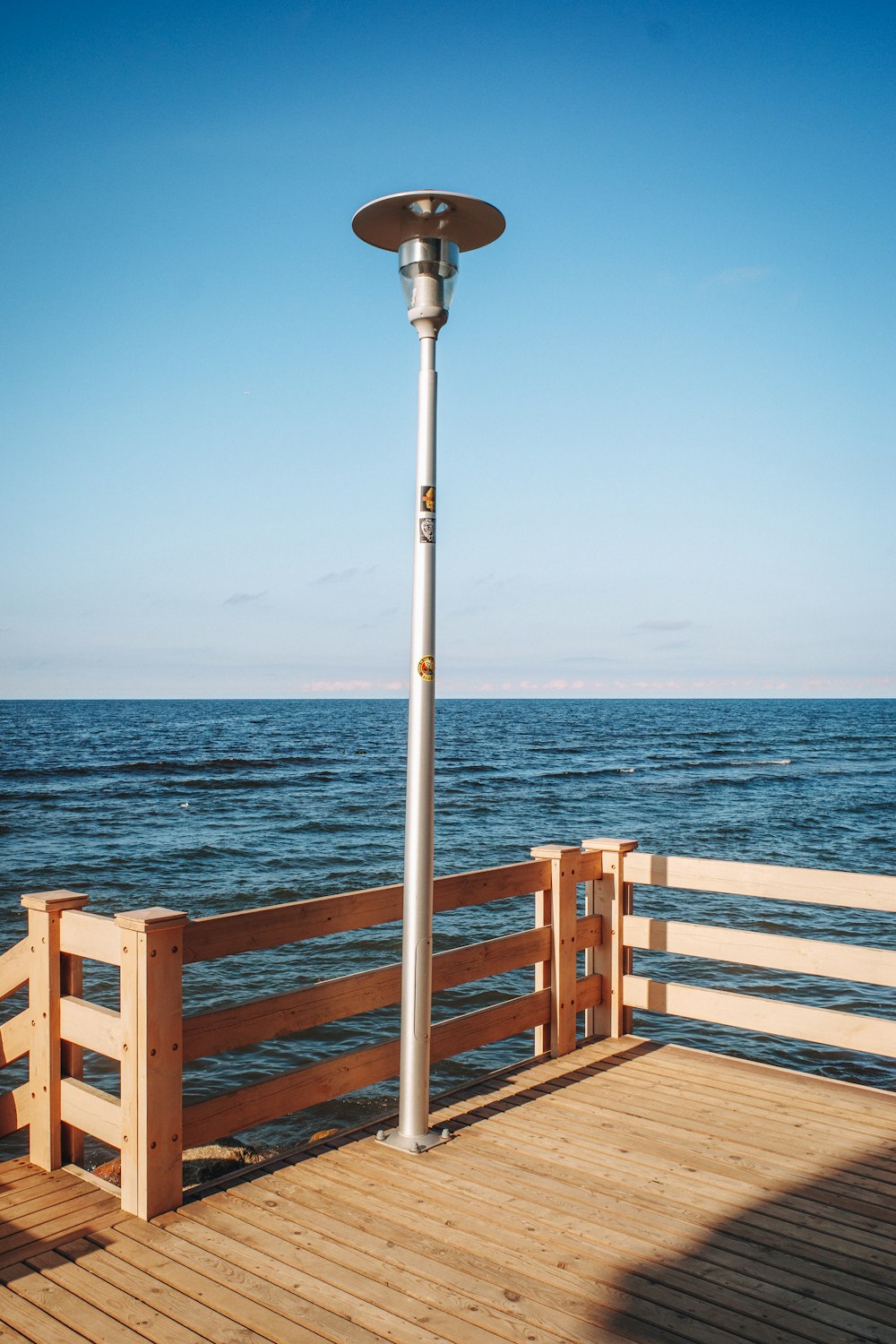 a lamp post on a wooden deck overlooking the ocean