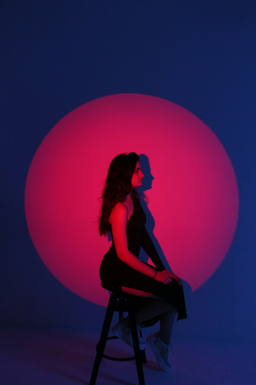 a woman sitting on a stool in front of a pink ball