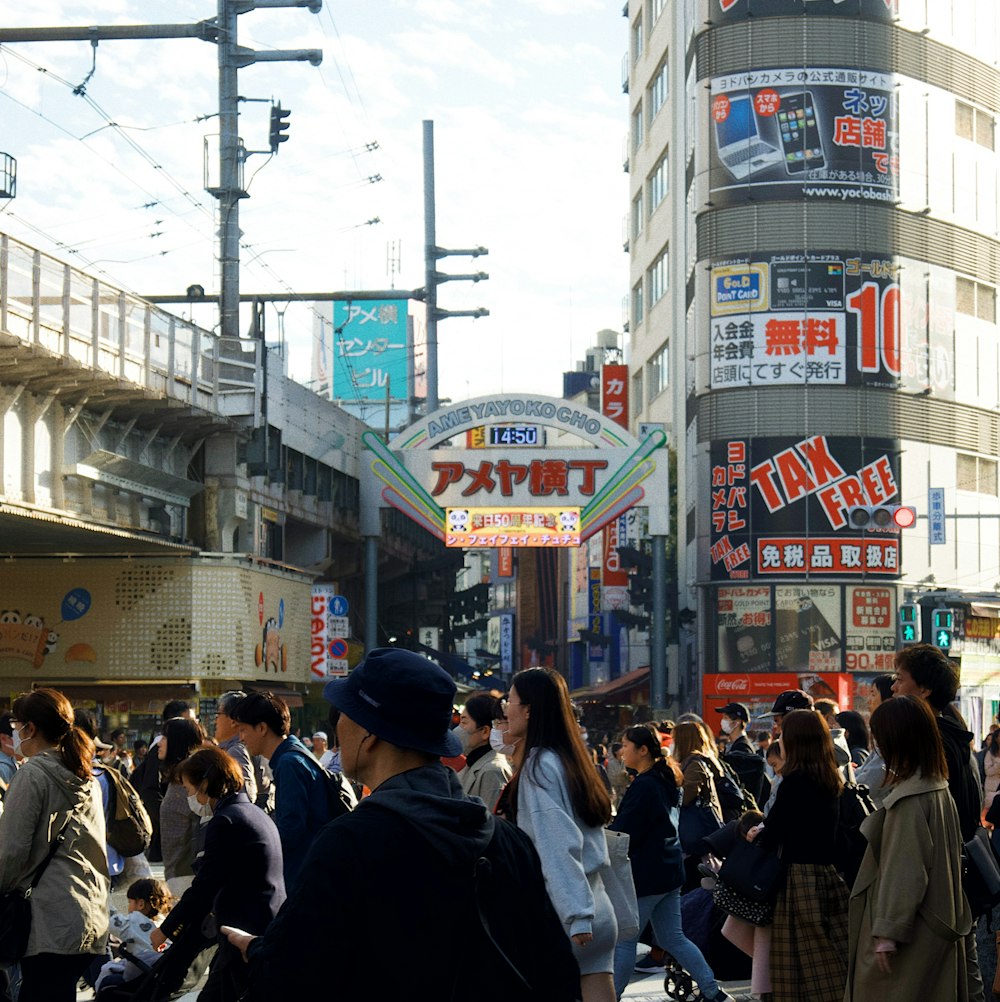 a crowd of people walking down a street next to tall buildings