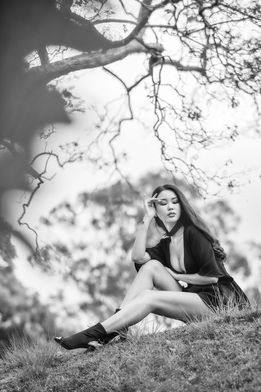 a woman sitting on a hill talking on a cell phone