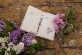 an open book sitting next to a bunch of flowers