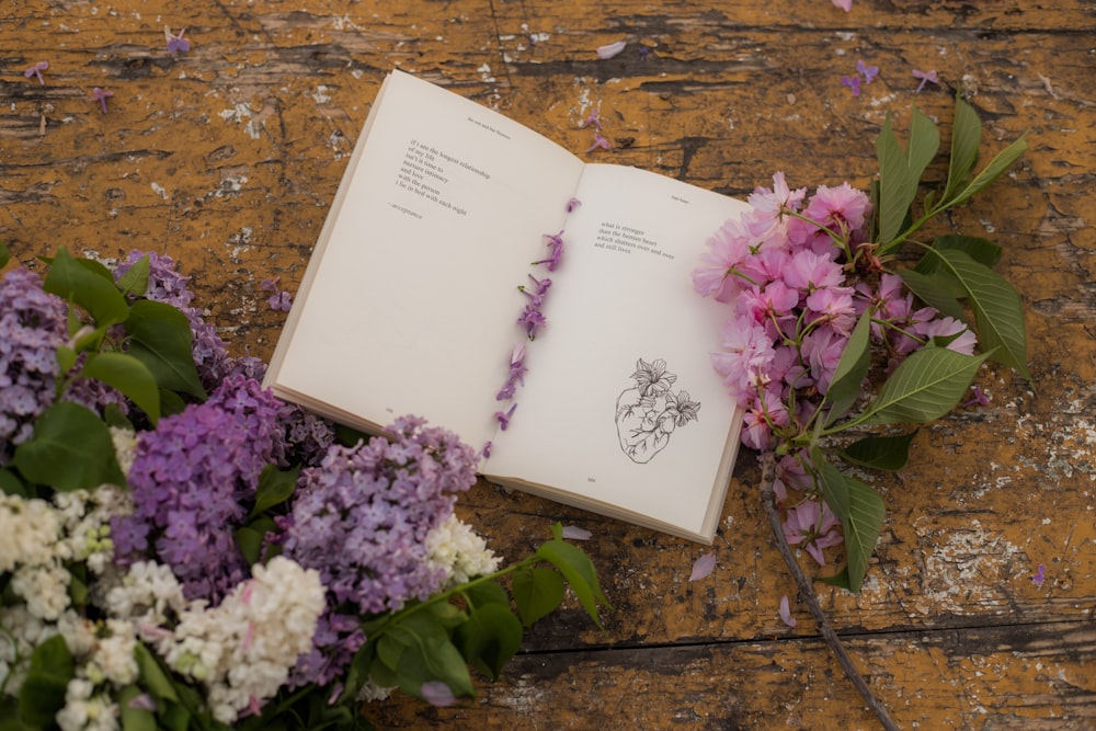 an open book sitting next to a bunch of flowers