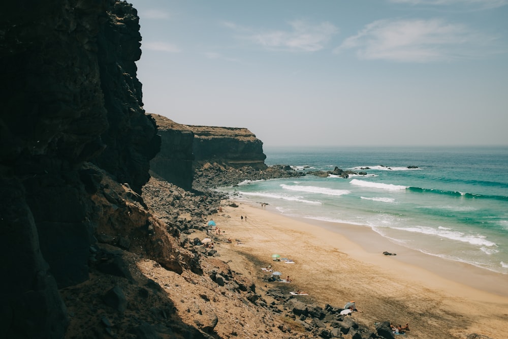 a sandy beach next to a rocky cliff