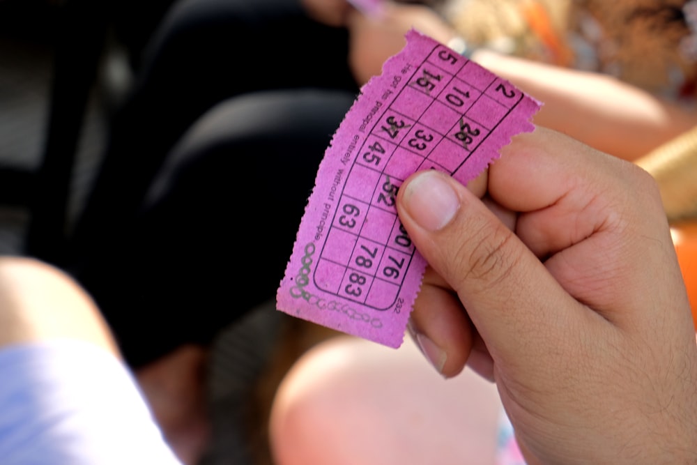 a person holding a pink ticket in their hand