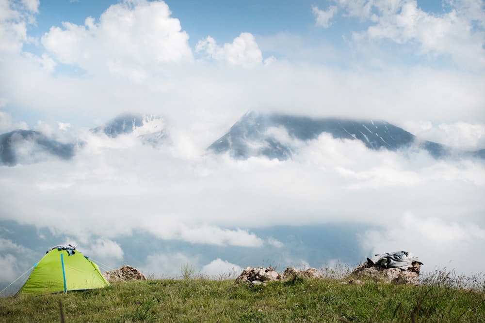a tent pitched up on top of a grassy hill