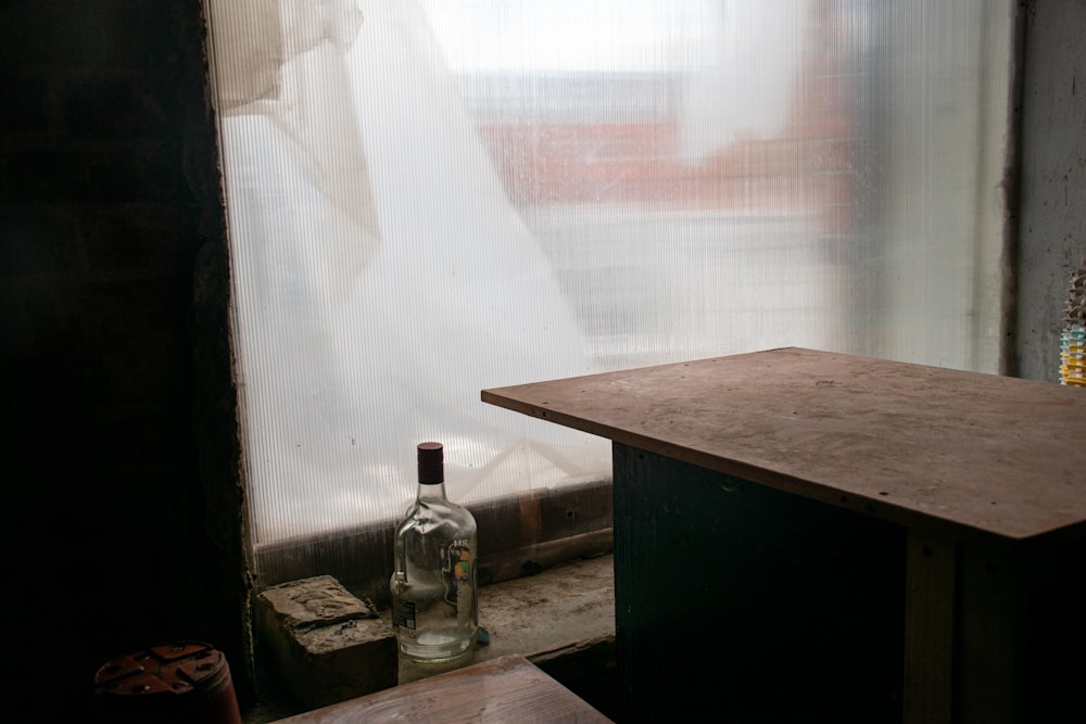 a bottle of wine sitting next to a window