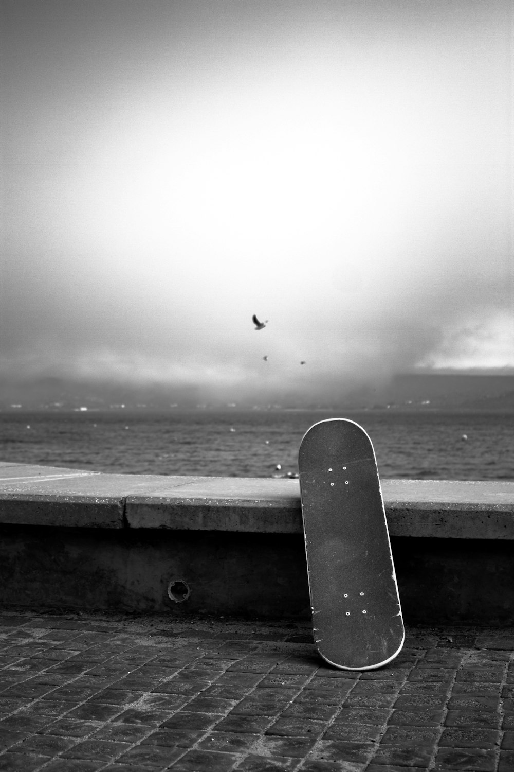 a black and white photo of a skateboard leaning against a wall