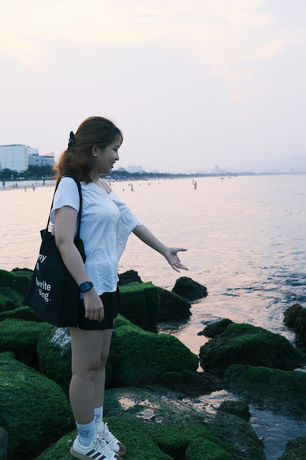 a woman is standing on some rocks by the water