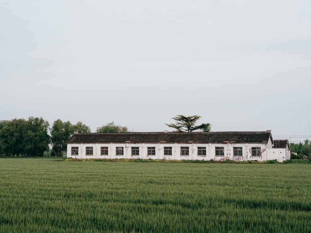 a white building in a green field with trees in the background