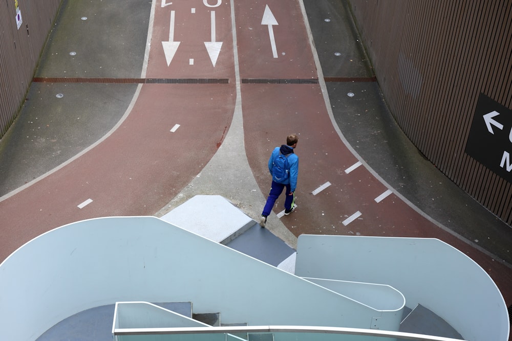 a man in a blue jacket walking down a street