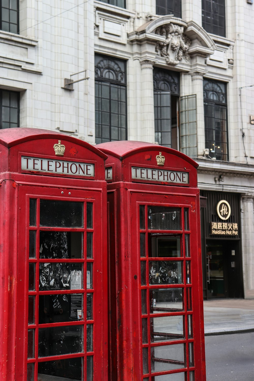 two red telephone booths in front of a building