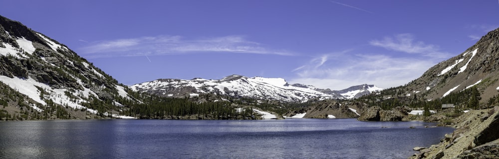 a lake surrounded by snow covered mountains under a blue sky