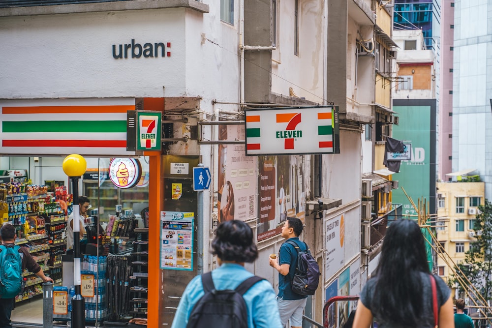 a group of people walking down a street next to a store