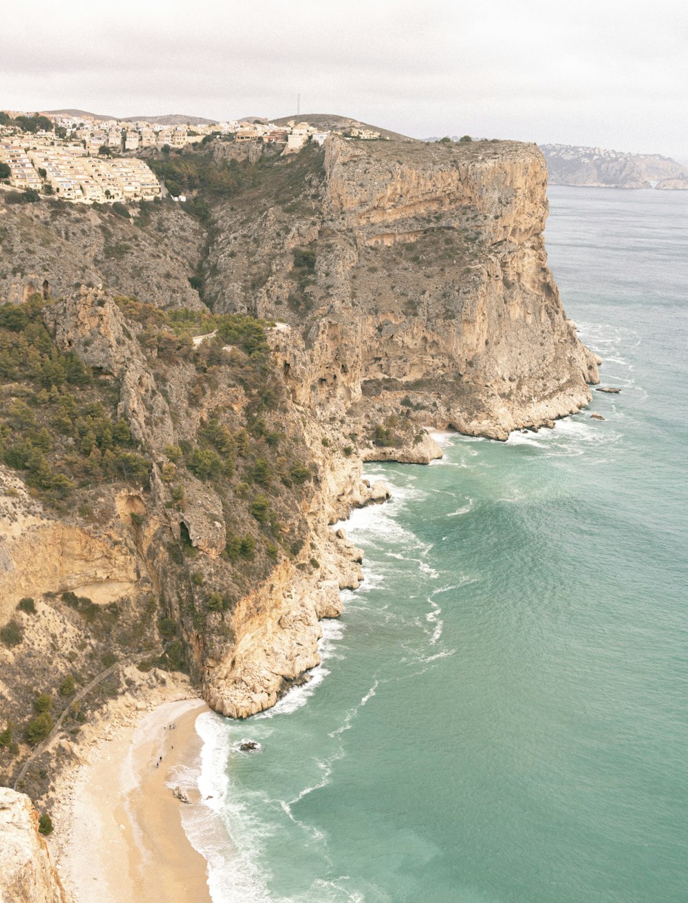 a beach next to a cliff with a body of water