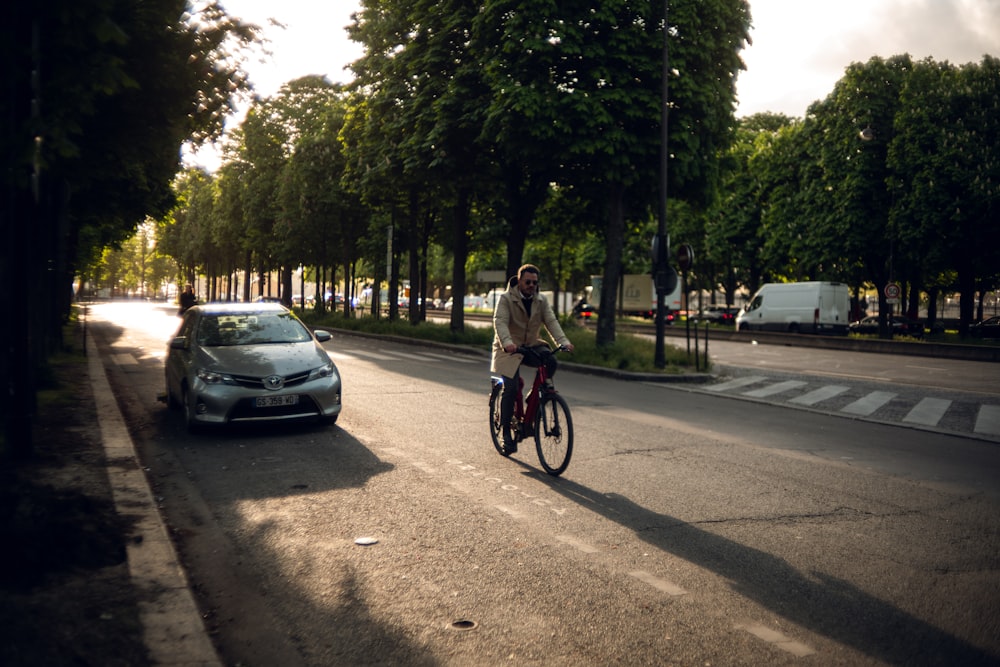 a man riding a bike down a street next to a car