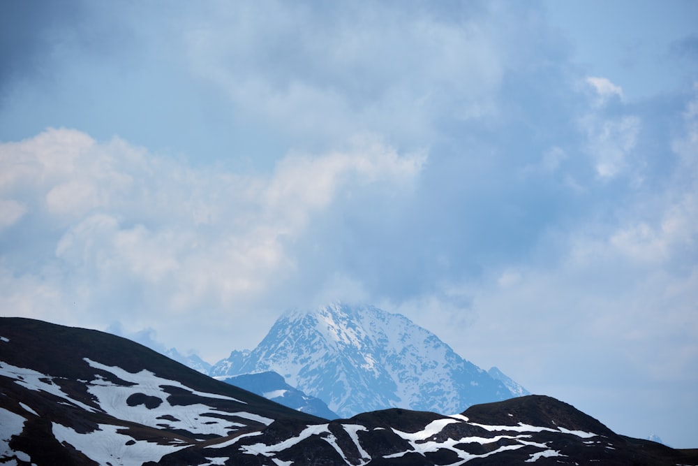 a snow covered mountain under a cloudy blue sky