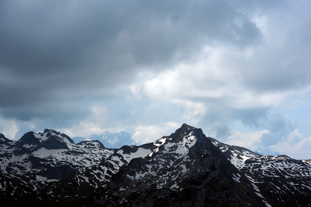 a group of mountains with snow on them under a cloudy sky