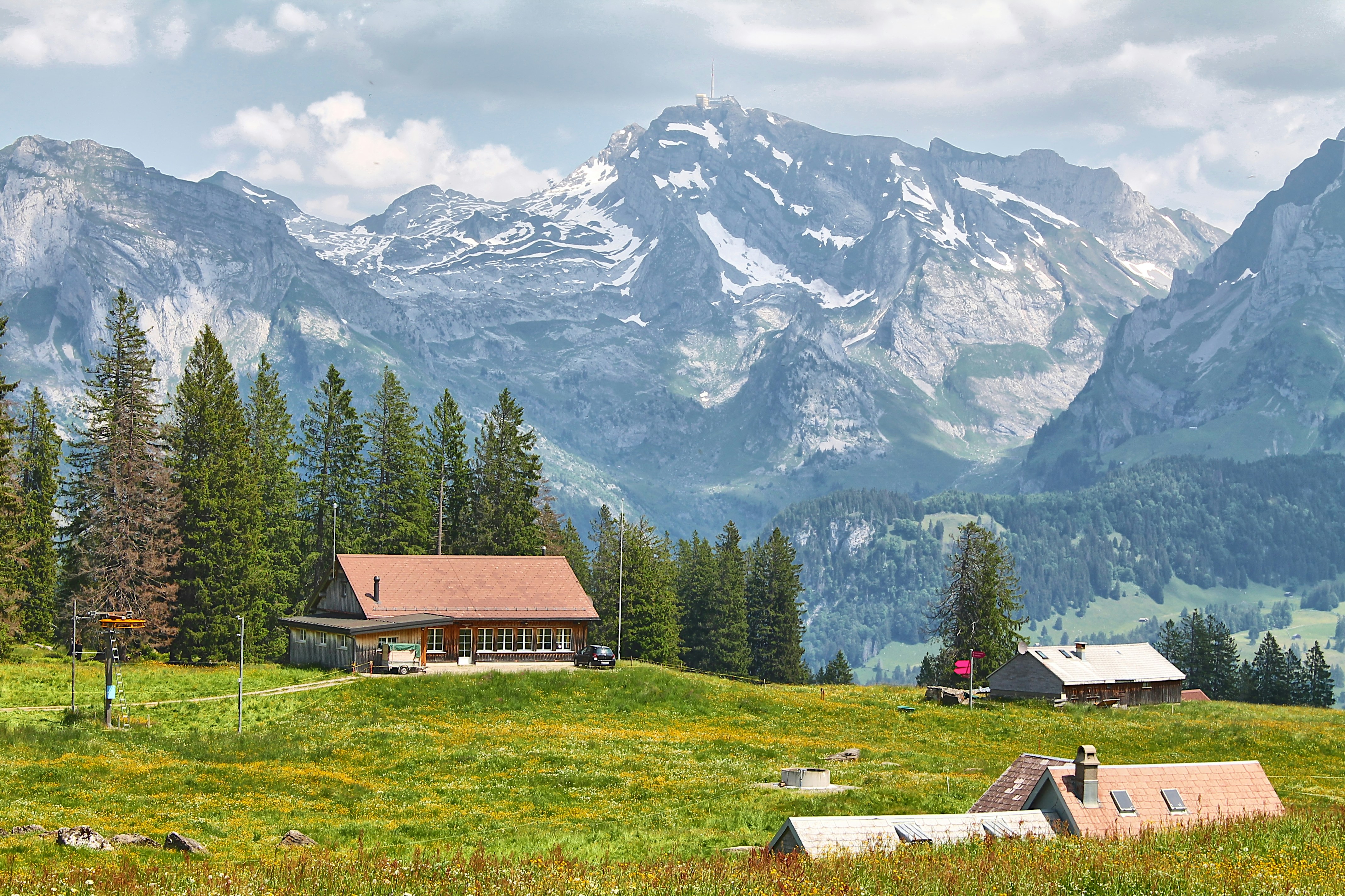 a cabin in the middle of a field with mountains in the background