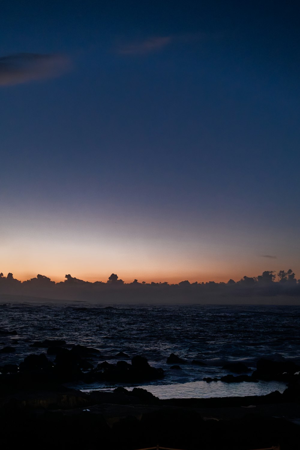 the sun is setting over the ocean on a cloudy day