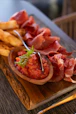 a wooden plate topped with meat and french fries