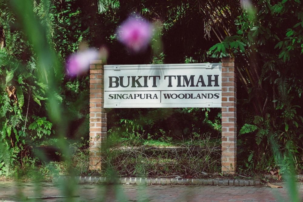 a sign in front of some trees and bushes