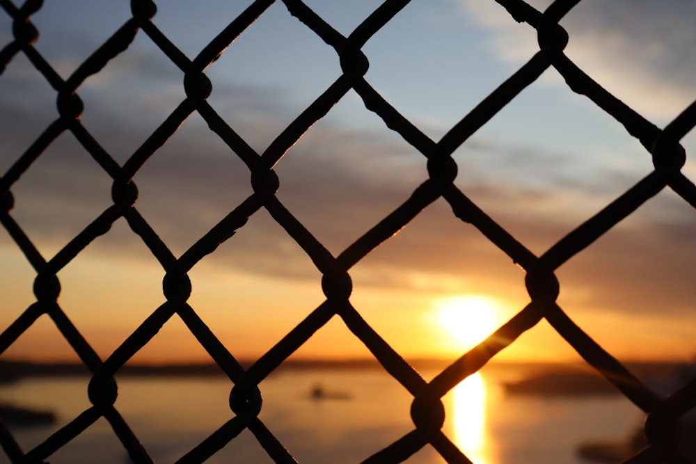 a sunset seen through a chain link fence