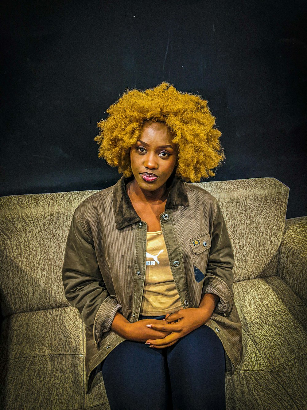 a woman sitting on top of a couch wearing a jacket
