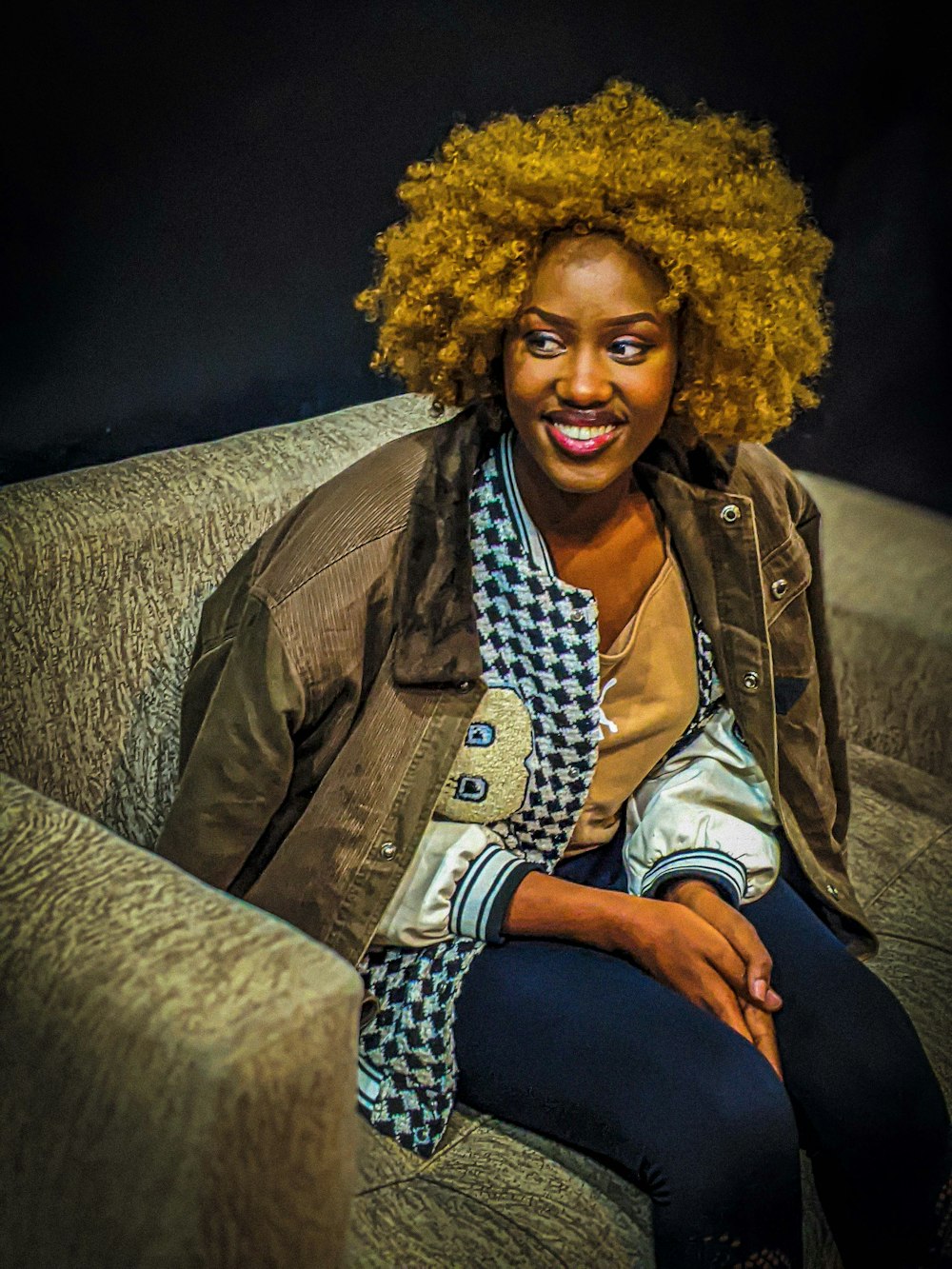 a woman sitting on a couch smiling at the camera