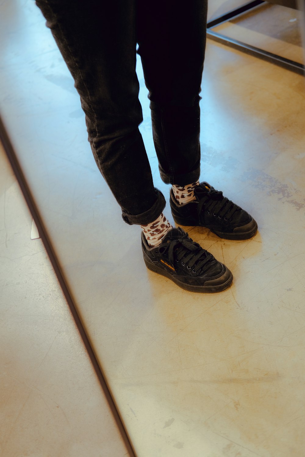 a person standing on a floor with black shoes