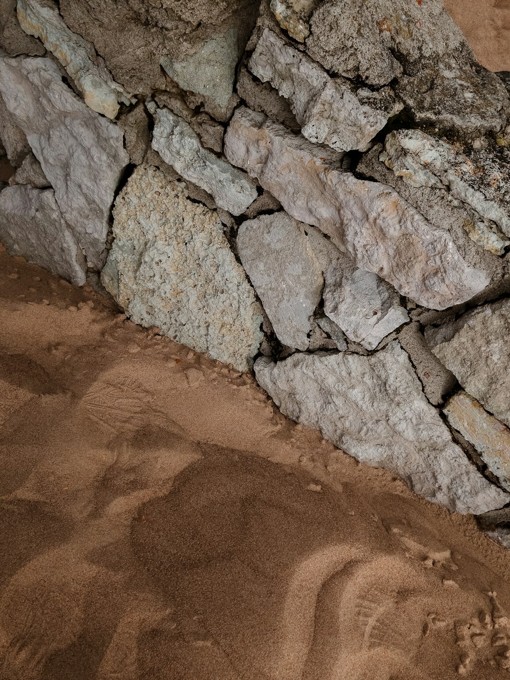 a pile of rocks sitting on top of a sandy ground